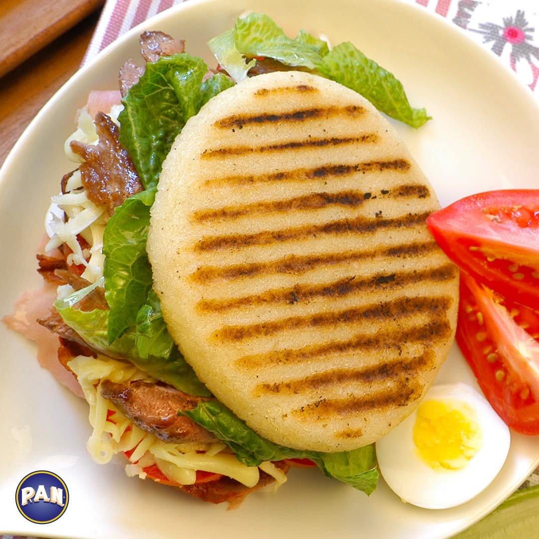 Grilled arepa stuffed with ham, cheese, beef and salad with boiled egg and tomato