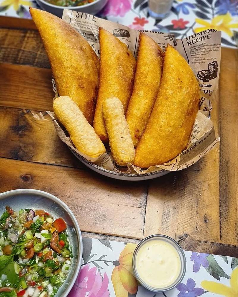 Basket of fried corn empanadas with tequenos and salad